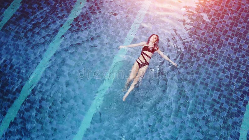 La photo aérienne de vue de dessus d'un modèle sexy séduisant dans des maillots de bain noirs apprécie vous détendre dans la pisci banque de vidéos