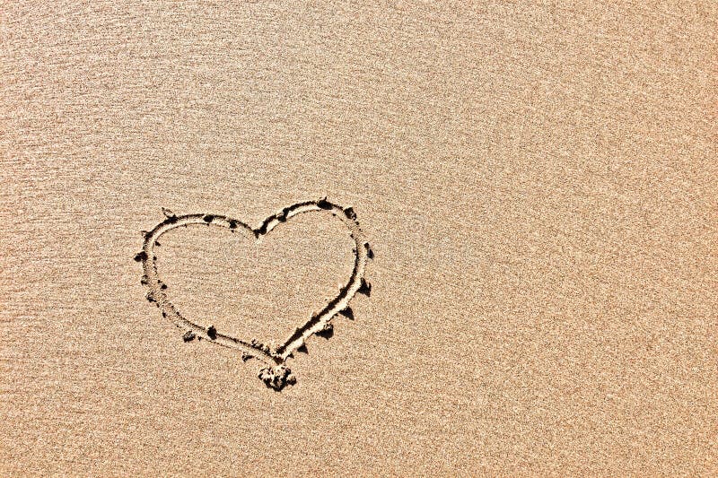 The photo captures a heart outline drawn in sand, highlighting its texture. The photo captures a heart outline drawn in sand, highlighting its texture.