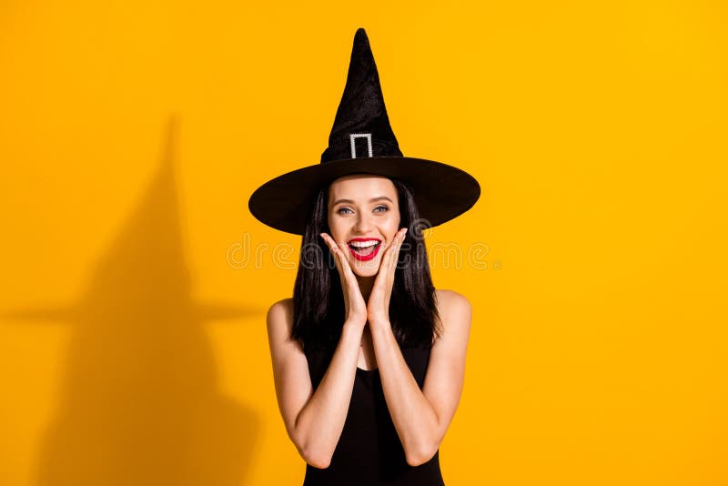 Photo of cute charming young magician lady hands face open mouth excited, receive compliment cute costume wear black wizard headwear dress isolated bright yellow color background. Photo of cute charming young magician lady hands face open mouth excited, receive compliment cute costume wear black wizard headwear dress isolated bright yellow color background
