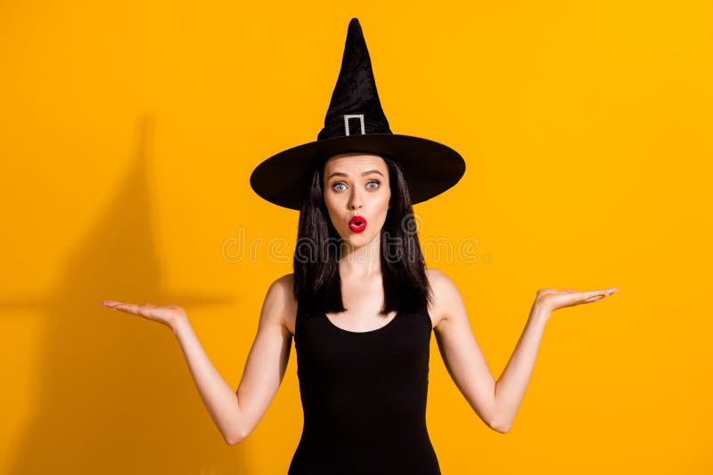 Photo of lovely charming young magician lady excited open palms hold empty space, allow you choose between best wear black wizard headwear dress isolated bright yellow color background. Photo of lovely charming young magician lady excited open palms hold empty space, allow you choose between best wear black wizard headwear dress isolated bright yellow color background