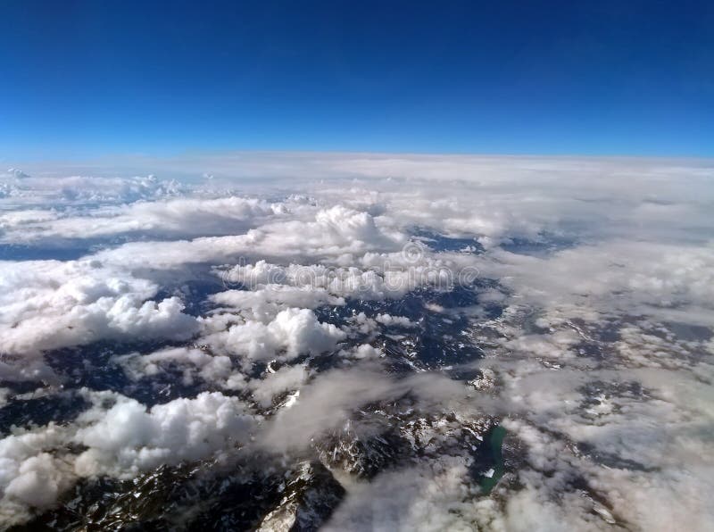 La photographie de haute altitude de la neige a couvert des alpes de ciel bleu et de nuages blancs couvrant la terre d'horizon in