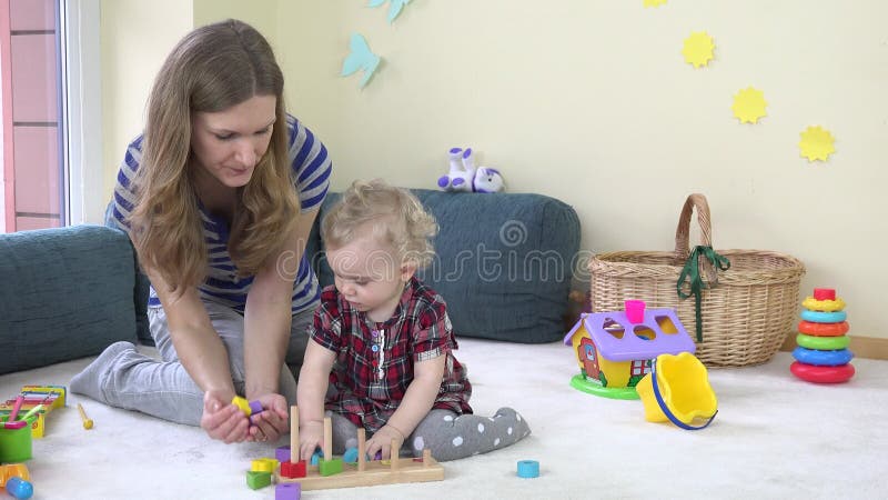 La piccola ragazza sveglia ha messo i mattoni di legno variopinti nelle palme della madre stock footage