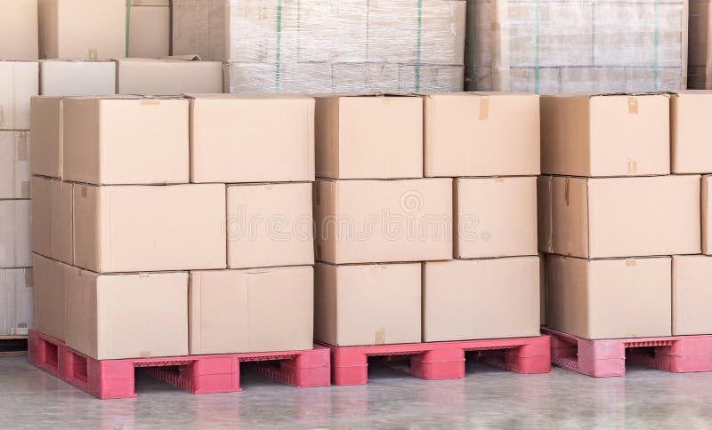 La pila de mercancías encuadierna las cajas en la plataforma roja en el almacén de la logística