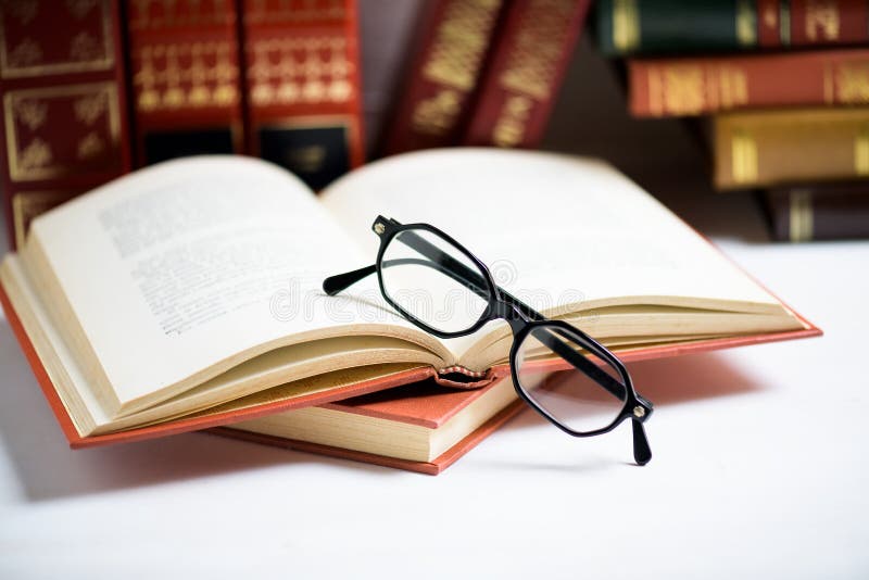 La pile de livres avec les verres des hommes de couleur a placé sur le livre ouvert dans la bibliothèque ou sur la table blanche photo stock La pile de livres avec les verres des hommes de couleur a placé sur le livre ouvert dans la bibliothèque ou sur la table blanche photo stock