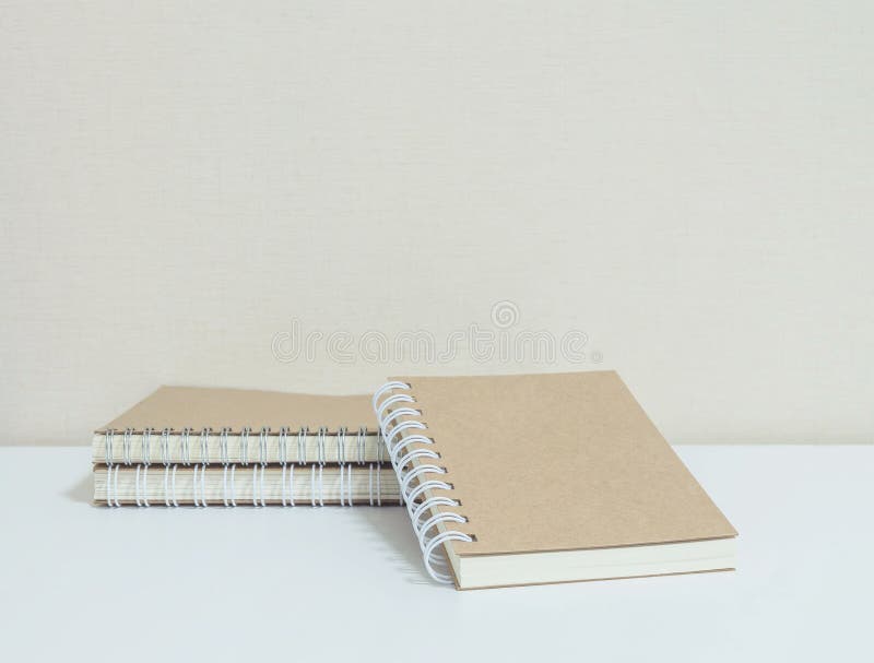 La pile de plan rapproché du carnet brun sur le bureau et le papier peint blancs dans la chambre a donné au fond une consistance photo stock La pile de plan rapproché du carnet brun sur le bureau et le papier peint blancs dans la chambre a donné au fond une consistance photo stock