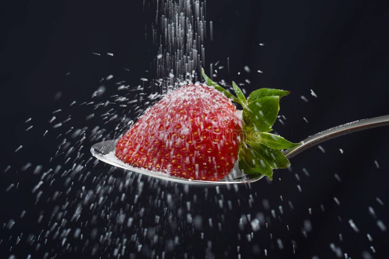 La pioggia dello zucchero spruzza sopra la fragola deliziosa sul cucchiaio che si rovescia fuori dappertutto fotografia stock