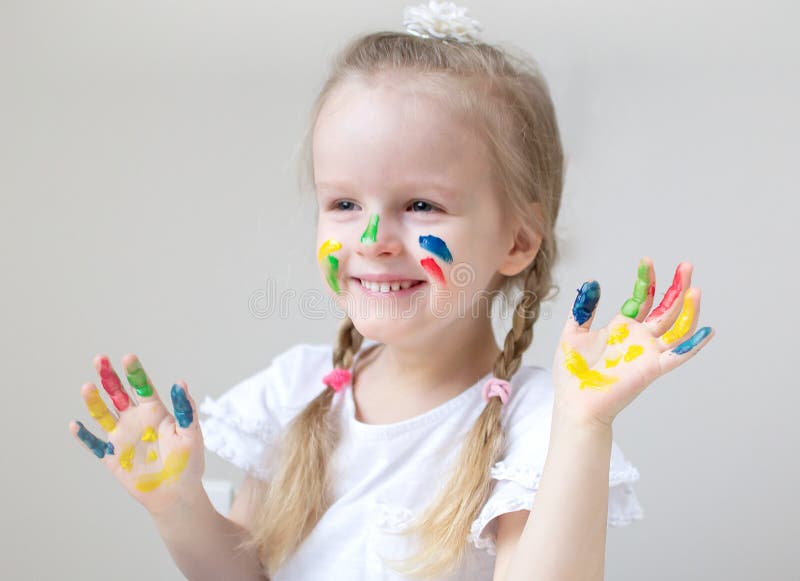La pittura caucasica della bambina con le mani variopinte dipinge a casa l'istruzione iniziale immagine stock La pittura caucasica della bambina con le mani variopinte dipinge a casa l'istruzione iniziale immagine stock
