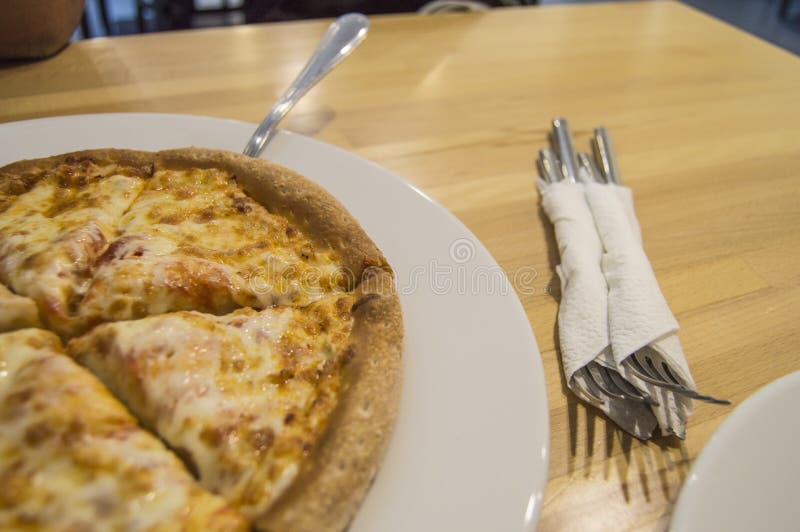 La pizza de queso recientemente cocida, corte apetitoso en pedazos miente en una placa blanca, una vista superior de la tabla y c foto de archivo La pizza de queso recientemente cocida, corte apetitoso en pedazos miente en una placa blanca, una vista superior de la tabla y c foto de archivo