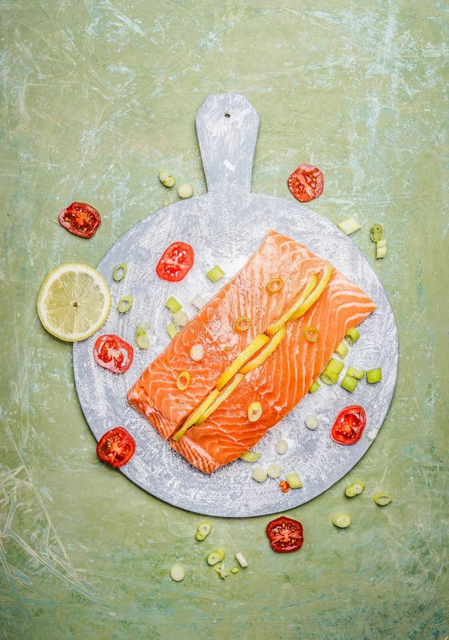 La porción de prendedero de color salmón fresco con el limón y los ingredientes el cocinar en el destripamiento redondo suben, vi fotografía de archivo La porción de prendedero de color salmón fresco con el limón y los ingredientes el cocinar en el destripamiento redondo suben, vi fotografía de archivo