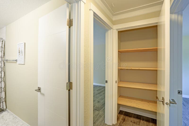 La porta bianca si apre ad una dispensa della cucina riempita di scaffali di legno immagini stock La porta bianca si apre ad una dispensa della cucina riempita di scaffali di legno immagini stock