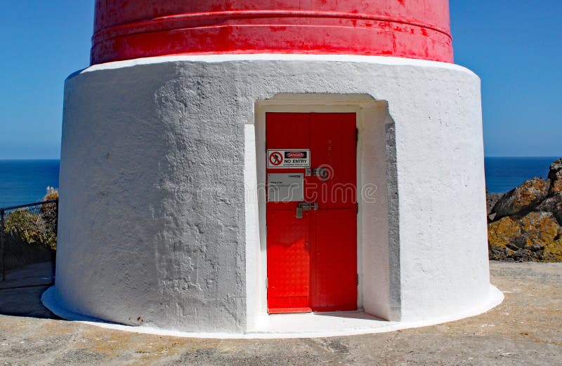 La porte d'entrée du phare rayé rouge et blanc au cap Palliser sur l'île du nord, Nouvelle-Zélande La lumière a été incorporée image libre de droits La porte d'entrée du phare rayé rouge et blanc au cap Palliser sur l'île du nord, Nouvelle-Zélande La lumière a été incorporée image libre de droits