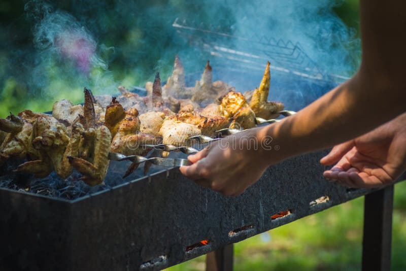 La preparación de los pinchos del pollo en un brasero en los pinchos, en la derecha en el marco de la mano, los pinchos se vuelca imagen de archivo La preparación de los pinchos del pollo en un brasero en los pinchos, en la derecha en el marco de la mano, los pinchos se vuelca imagen de archivo