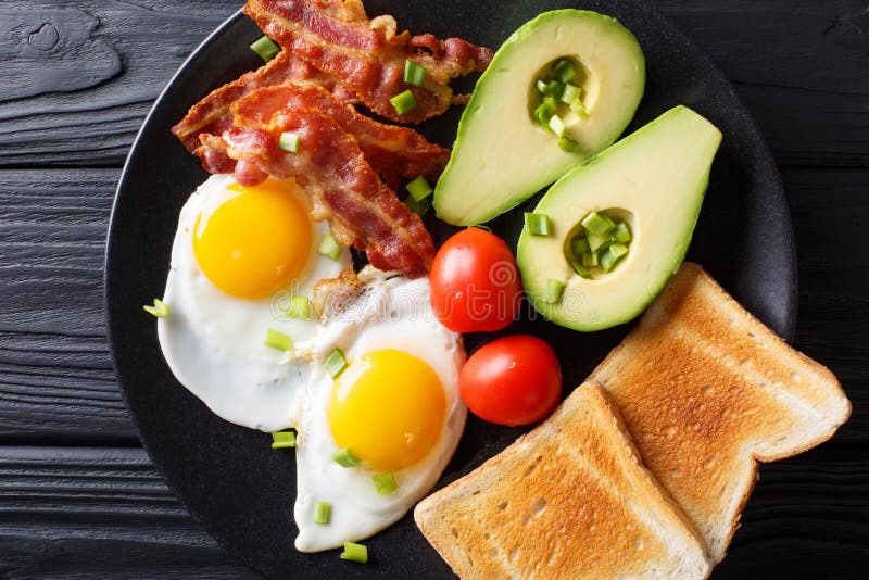 La prima colazione deliziosa delle uova con bacon croccante, avocado, tosta immagine stock La prima colazione deliziosa delle uova con bacon croccante, avocado, tosta immagine stock