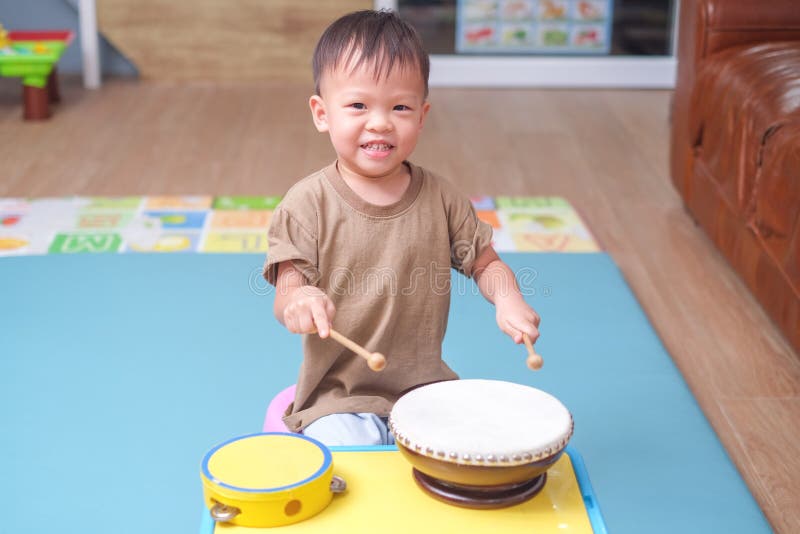 La Prise D'enfant De Bébé Garçon D'enfant En Bas âge Colle Et Joue Un  Tambour D'instrument De Musique Photo stock - Image du chinois, enfants:  138939472