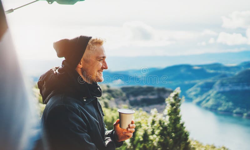 La prise de touristes de hippie dans la tasse de mains de la boisson chaude, sourire isolé de type apprécient la montagne de fusé photo stock La prise de touristes de hippie dans la tasse de mains de la boisson chaude, sourire isolé de type apprécient la montagne de fusé photo stock