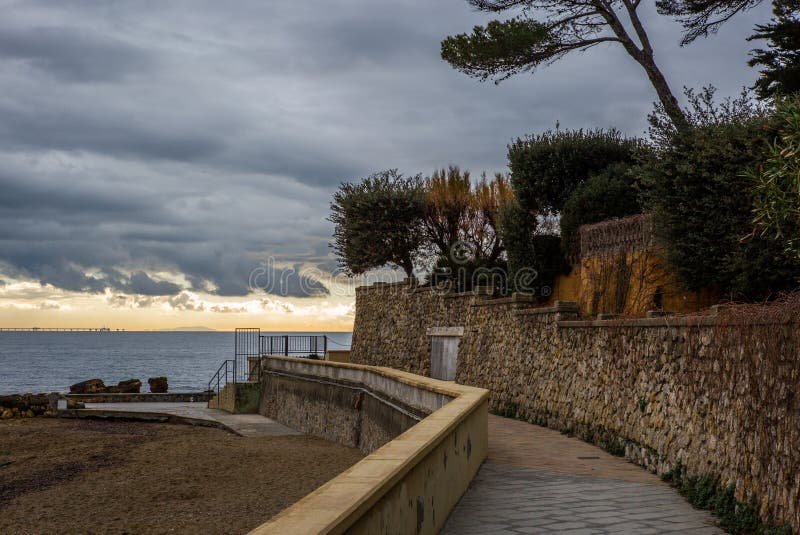 La promenade de Castiglioncello en Toscane en hiver au coucher du soleil avec l'île sur l'horizon - 1 images stock La promenade de Castiglioncello en Toscane en hiver au coucher du soleil avec l'île sur l'horizon - 1 images stock