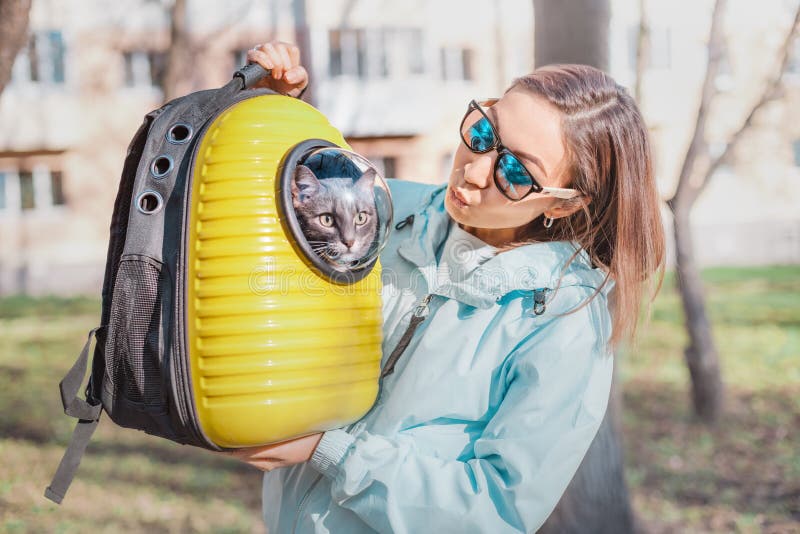 Happy Girl pet owner smiles in the Park walking with her cat. Friendship and cat carrier. Lifestyle and recreation. Happy Girl pet owner smiles in the Park walking with her cat. Friendship and cat carrier. Lifestyle and recreation