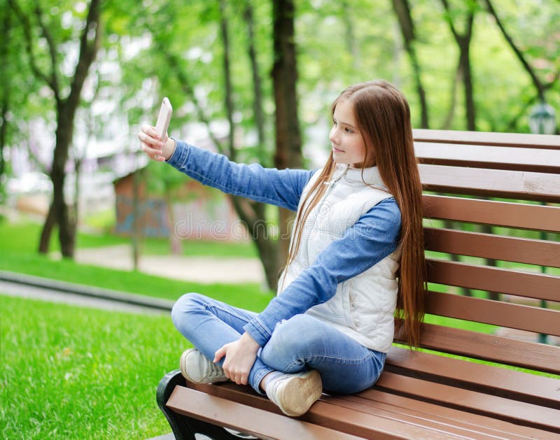La préadolescent souriant mignonne de cette petite fille prend le selfie et utilise le téléphone smartphone image stock