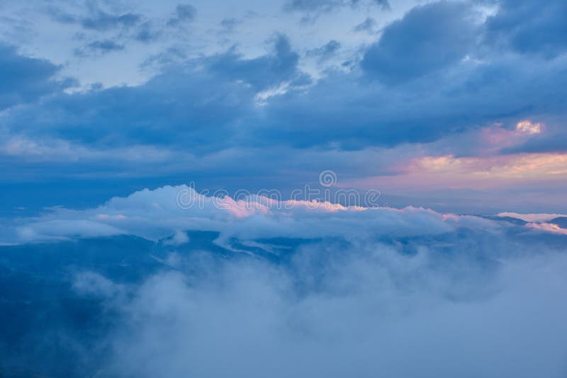 La puesta del sol ilumina las nubes sobre un valle verde de la montaña en la niebla imágenes de archivo libres de regalías La puesta del sol ilumina las nubes sobre un valle verde de la montaña en la niebla imágenes de archivo libres de regalías