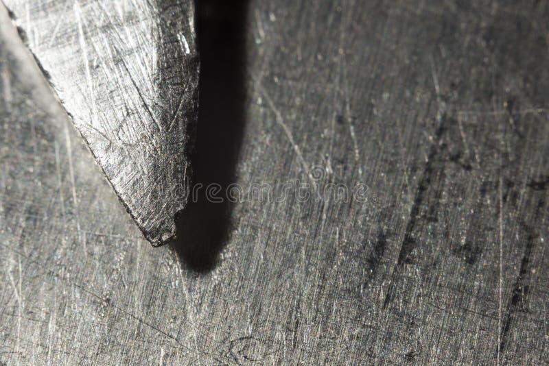 La punta di una lama nociva di un coltello su un fondo metallico, macro fotografie stock La punta di una lama nociva di un coltello su un fondo metallico, macro fotografie stock