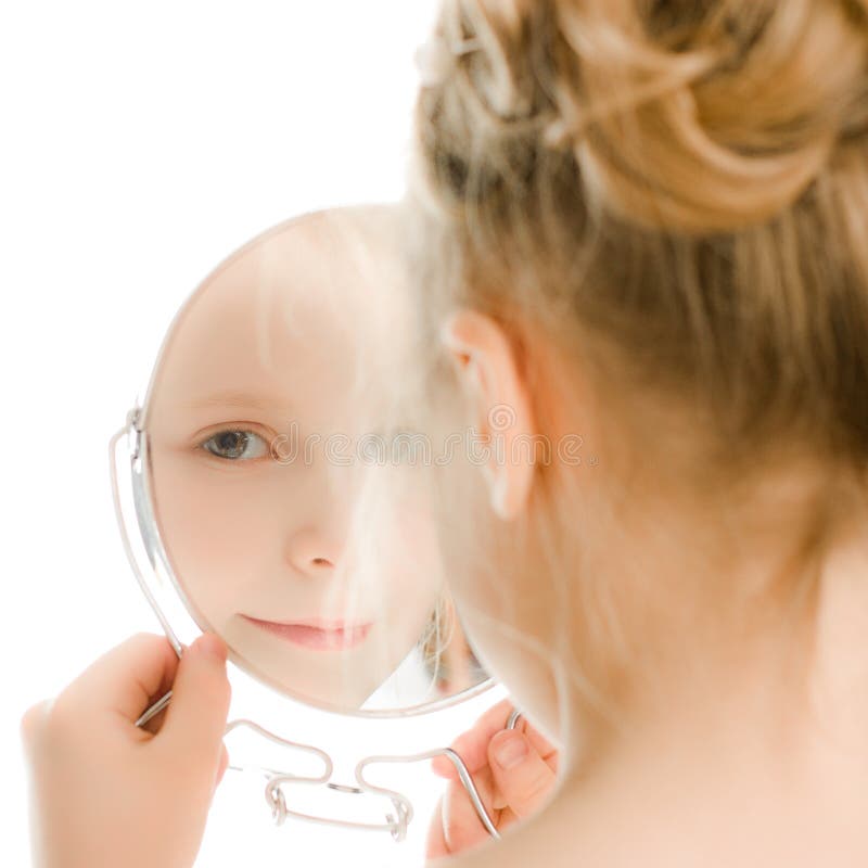 La ragazza abbastanza bella guarda nello specchio. immagini stock La ragazza abbastanza bella guarda nello specchio. immagini stock