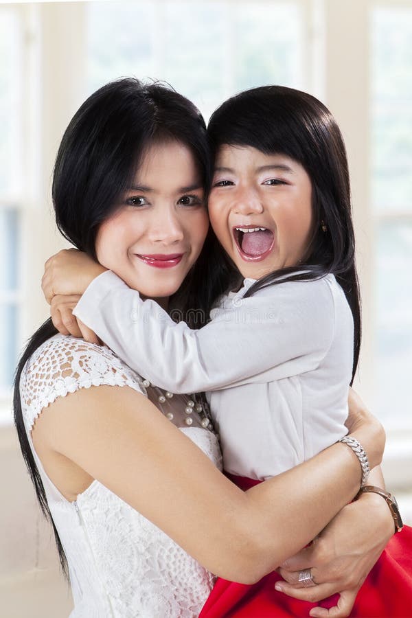 La ragazza allegra abbraccia sua madre a casa fotografia stock La ragazza allegra abbraccia sua madre a casa fotografia stock