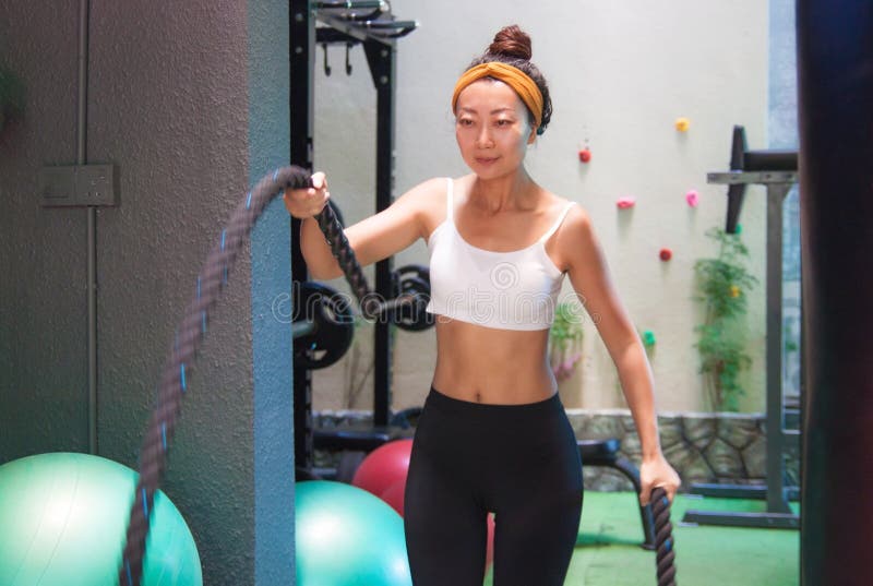 La ragazza attiva fa l'esercizio con le corde di forma fisica nella palestra immagine stock libera da diritti La ragazza attiva fa l'esercizio con le corde di forma fisica nella palestra immagine stock libera da diritti