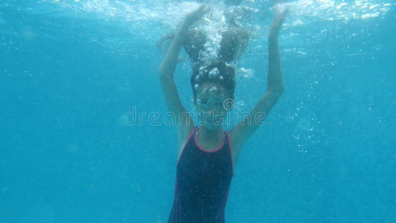La ragazza castana e teenager nuota sotto l'acqua Fucilazione subacquea 4K Movimento lento