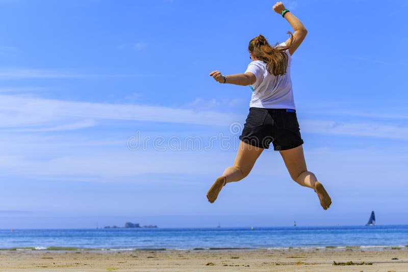 La ragazza che salta sulla spiaggia immagine stock La ragazza che salta sulla spiaggia immagine stock