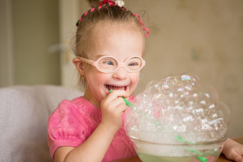 Girl with Down syndrome makes breathing speech therapy exercise. Girl with Down syndrome makes breathing speech therapy exercise