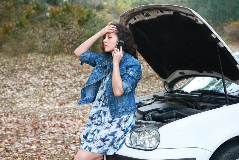 La ragazza con un'automobile rotta, apre il cappuccio, richiesta per aiuto fotografie stock libere da diritti La ragazza con un'automobile rotta, apre il cappuccio, richiesta per aiuto fotografie stock libere da diritti