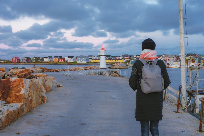 La ragazza con uno zaino che va al segnale sull'attracco in Vardo, Norvegia fotografia stock La ragazza con uno zaino che va al segnale sull'attracco in Vardo, Norvegia fotografia stock