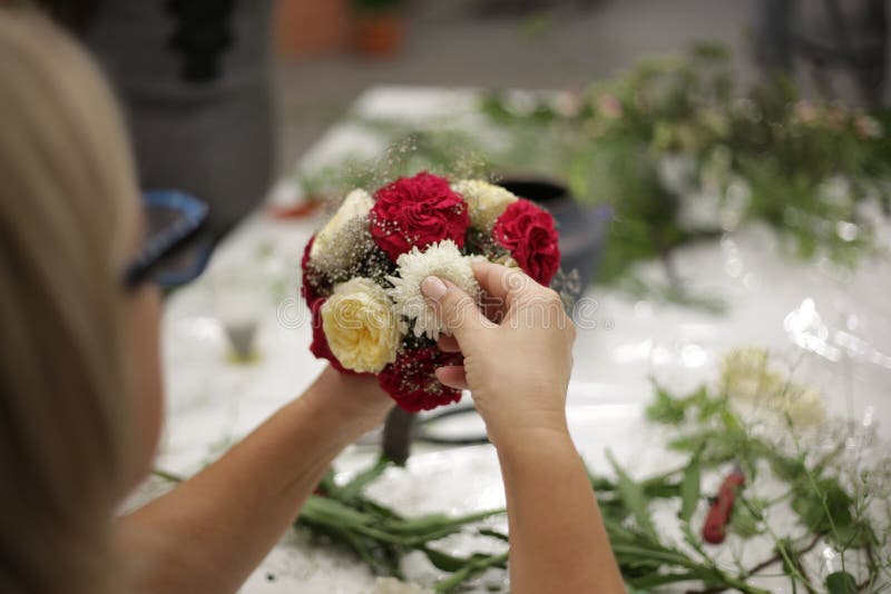 La ragazza decora un mazzo dai fiori differenti fotografie stock La ragazza decora un mazzo dai fiori differenti fotografie stock