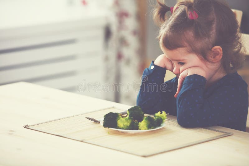 La ragazza del bambino non gradisce e non vuole mangiare le verdure fotografie stock libere da diritti La ragazza del bambino non gradisce e non vuole mangiare le verdure fotografie stock libere da diritti