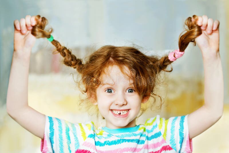 La ragazza di risata alz tirandoare a mano la sua treccia e le mostra i teeths C fotografie stock La ragazza di risata alz tirandoare a mano la sua treccia e le mostra i teeths C fotografie stock