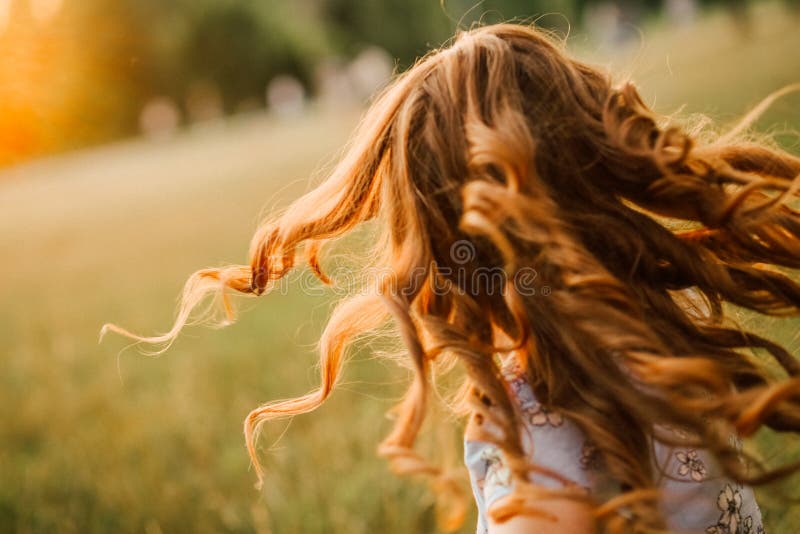 La ragazza esegue i riccioli dei capelli sviluppa il sole di incandescenza fotografia stock La ragazza esegue i riccioli dei capelli sviluppa il sole di incandescenza fotografia stock