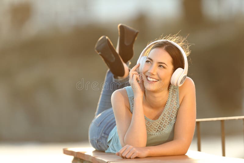 La ragazza felice ascolta musica che esamina il lato fotografia stock libera da diritti La ragazza felice ascolta musica che esamina il lato fotografia stock libera da diritti