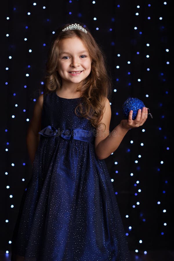 La ragazza graziosa del bambino sta tenendo la palla blu di natale fotografia stock La ragazza graziosa del bambino sta tenendo la palla blu di natale fotografia stock