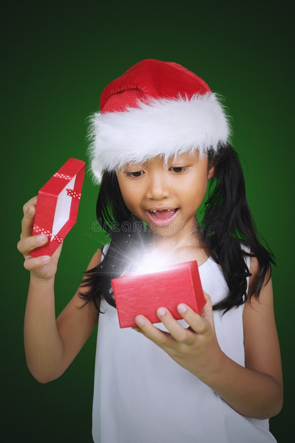 La ragazza impressionata apre un regalo di Natale immagine stock La ragazza impressionata apre un regalo di Natale immagine stock