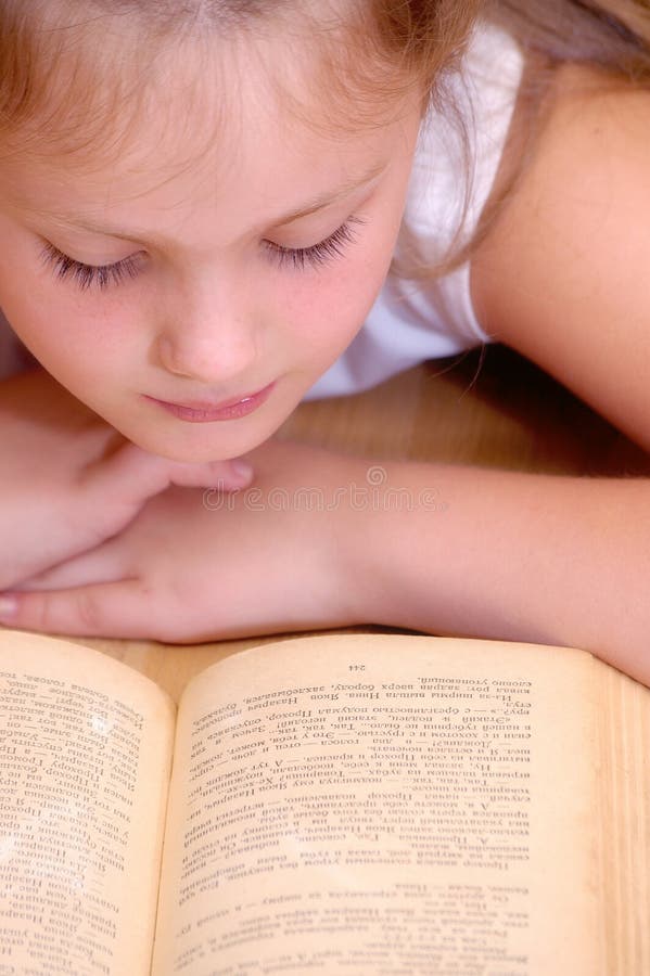 Una ragazza legge un libro antico fotografia stock libera da diritti