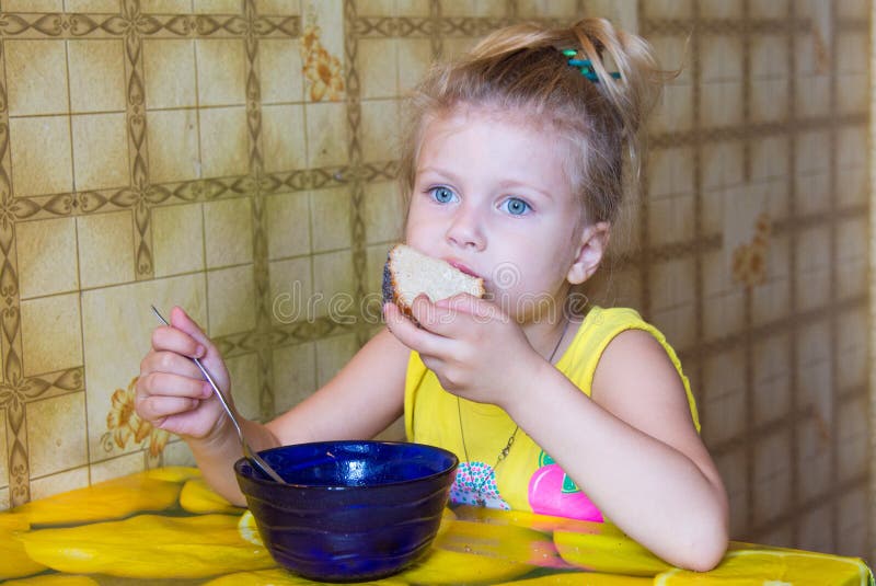 la ragazza morde fuori un pezzo di pane che mangia la minestra fotografie stock libere da diritti la ragazza morde fuori un pezzo di pane che mangia la minestra fotografie stock libere da diritti