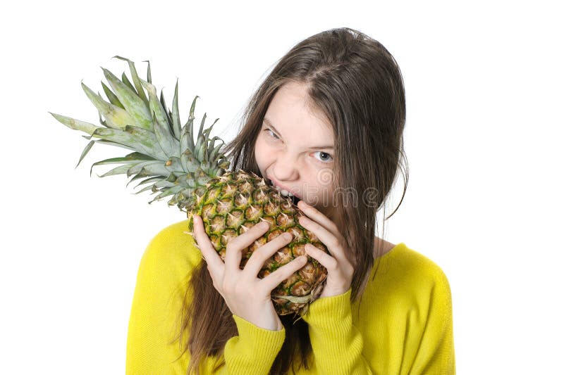 La ragazza morde in un grande ananas maturo fotografia stock libera da diritti La ragazza morde in un grande ananas maturo fotografia stock libera da diritti