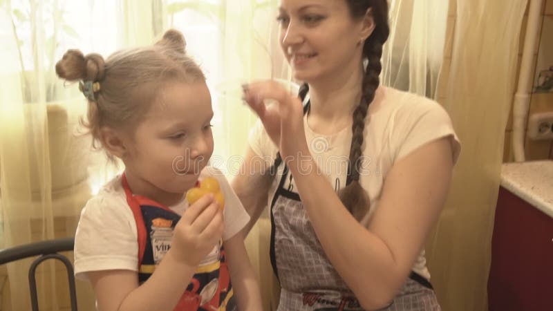 La ragazza nella cucina con la mia mamma mangia un pepe giallo