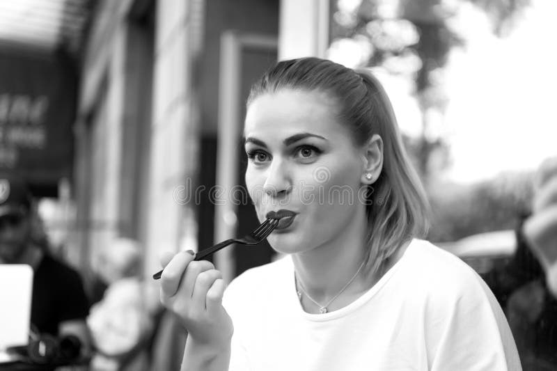 La ragazza o la donna mangia con la forcella in caffè a Parigi