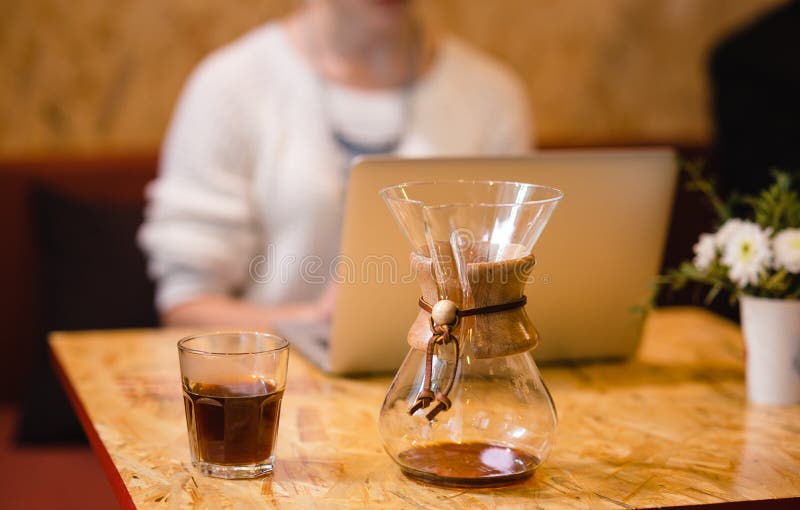 La ragazza russa sta bevendo il caffè in un caffè con un computer portatile immagini stock libere da diritti La ragazza russa sta bevendo il caffè in un caffè con un computer portatile immagini stock libere da diritti