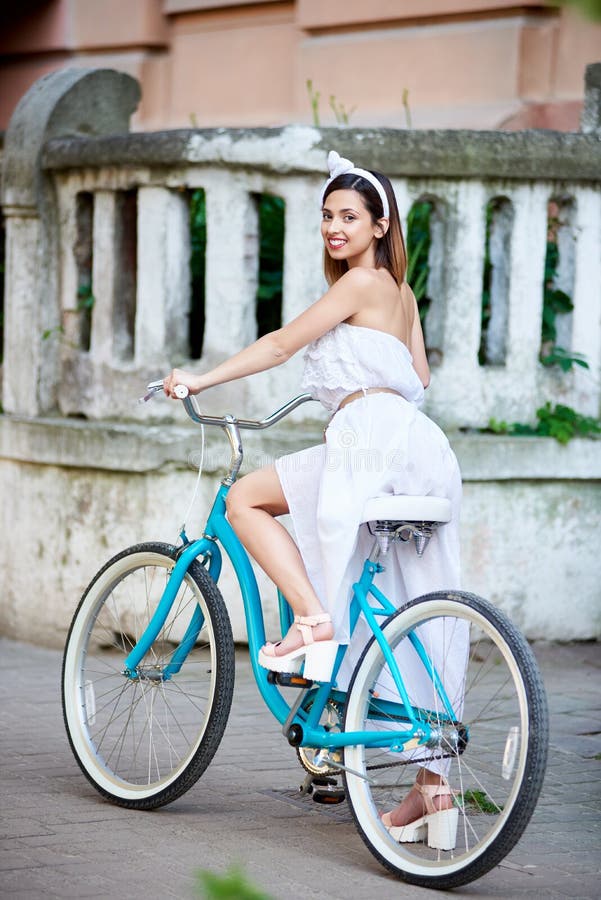 La ragazza si siede sulla retro bicicletta contro la vecchia costruzione del contesto immagine stock La ragazza si siede sulla retro bicicletta contro la vecchia costruzione del contesto immagine stock