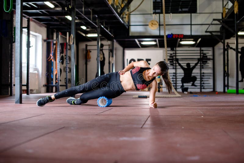 La ragazza sta esercitandosi sul pavimento della palestra immagine stock libera da diritti La ragazza sta esercitandosi sul pavimento della palestra immagine stock libera da diritti