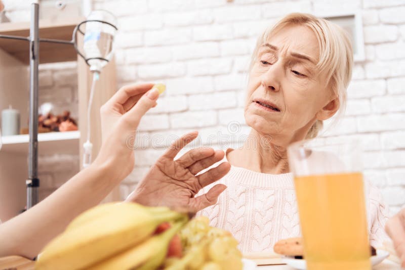 La ragazza sta occupandosi della donna anziana a casa La ragazza porta la prima colazione sul vassoio La donna sta rifiutando di fotografia stock La ragazza sta occupandosi della donna anziana a casa La ragazza porta la prima colazione sul vassoio La donna sta rifiutando di fotografia stock