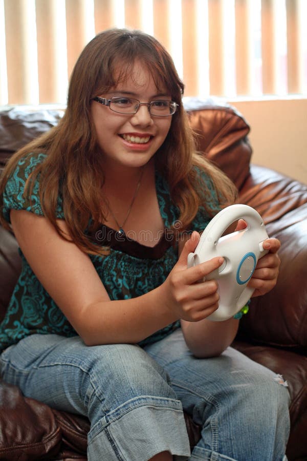 La ragazza teenager gioca il video gioco della corsa fotografie stock La ragazza teenager gioca il video gioco della corsa fotografie stock