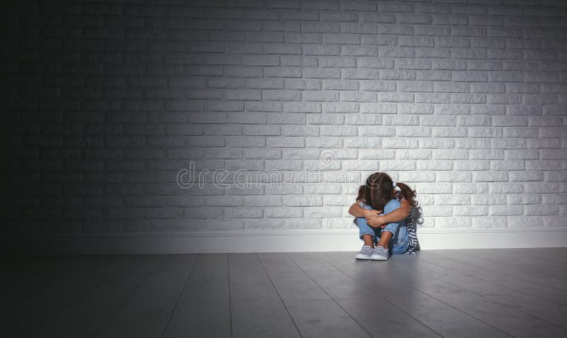 La ragazza triste triste turbata del bambino nello sforzo grida ad una parete scura vuota fotografia stock libera da diritti